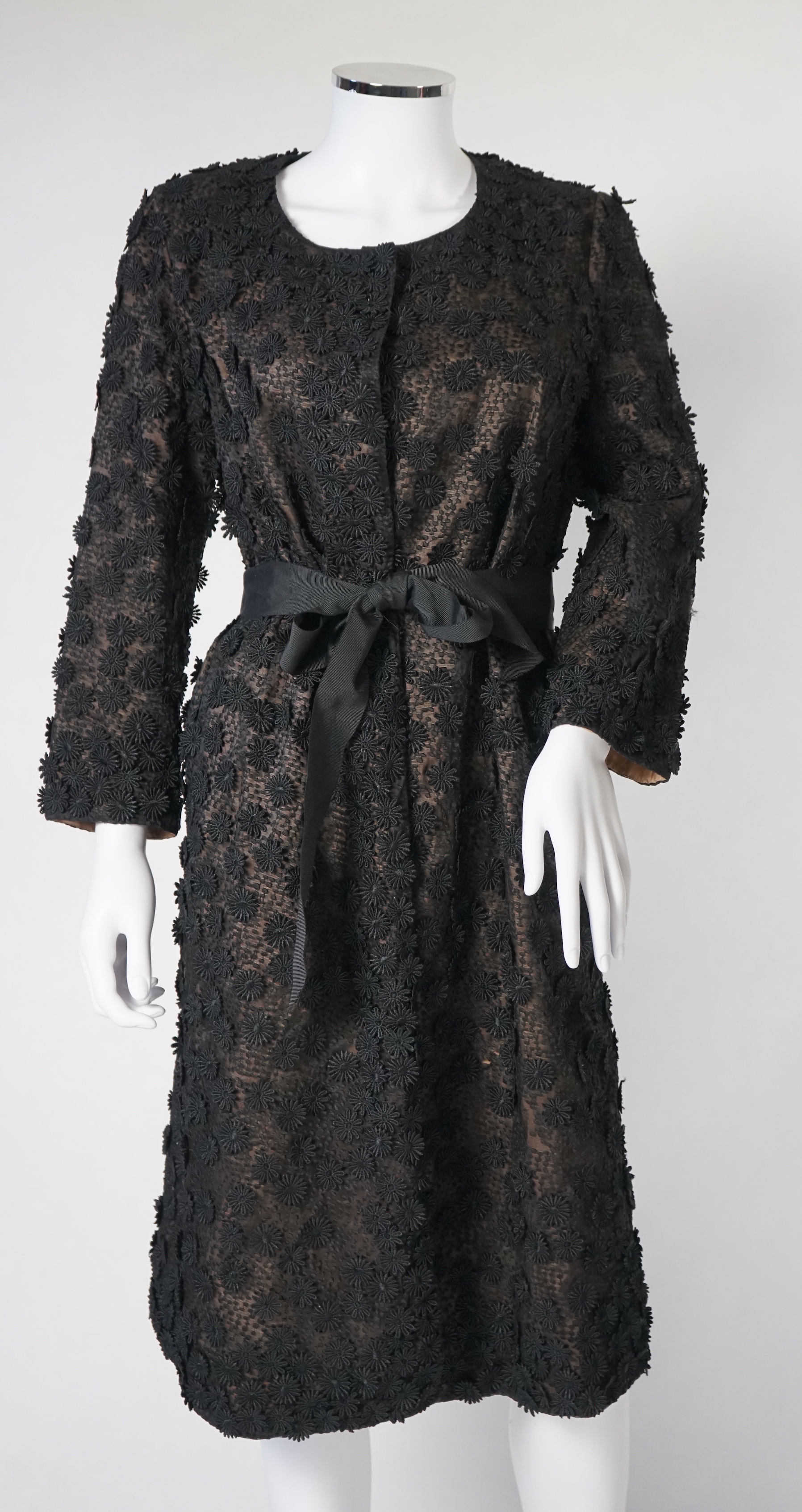 A Nicole Farhi lady's black lace knee length jacket with flower embellishment all over with black ribbon tie belt, size 12